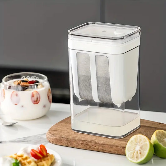 Clear container with a white lid on a wooden cutting board, surrounded by food items. Greek Youghurt maker